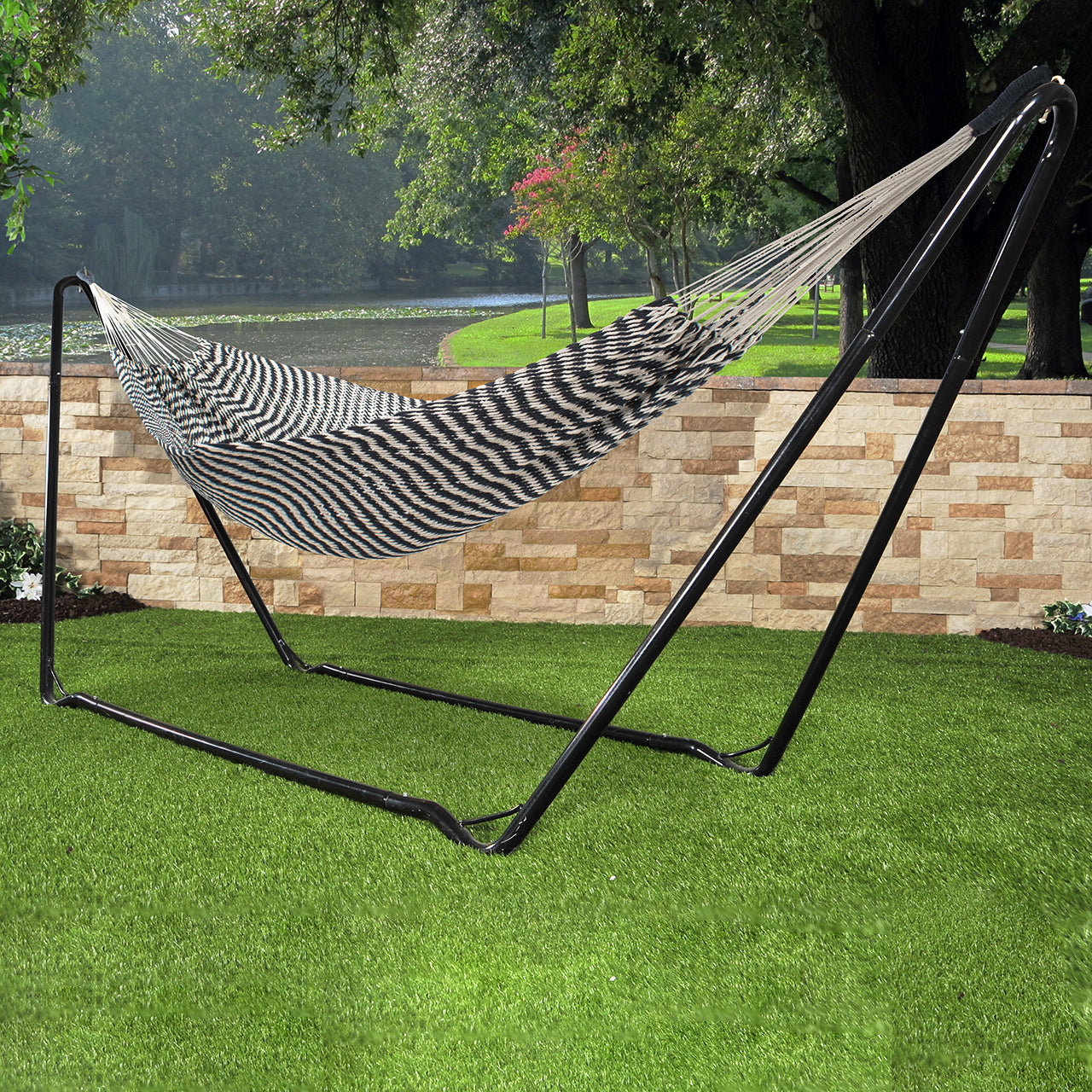 Bliss Hammocks 34-inch Wide Brazilian Style Black and White Rope Hammock hung on a hammock stand outside on grass.