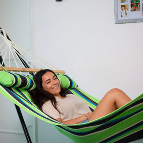 Woman smiling and laying in a Bliss Hammocks 48-inch Wide Caribbean Hammock attached to a hammock stand in a house.