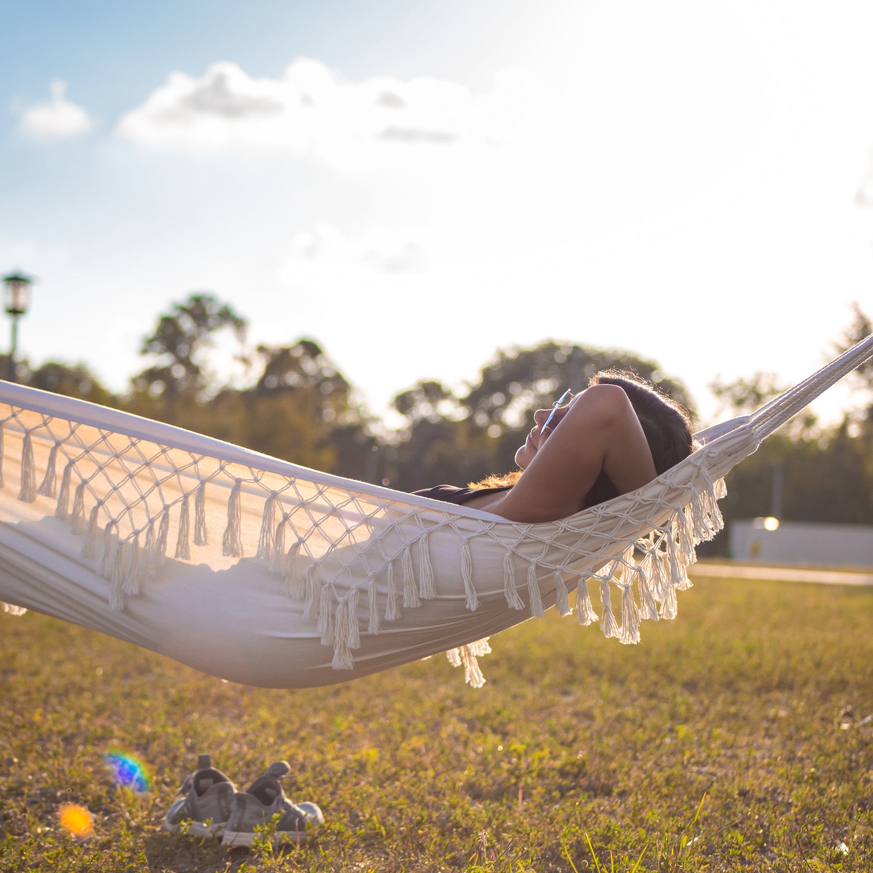 Woman relaxing outside in the Bliss Hammocks 40-inch Wide Hammock in a Bag with Fringe.