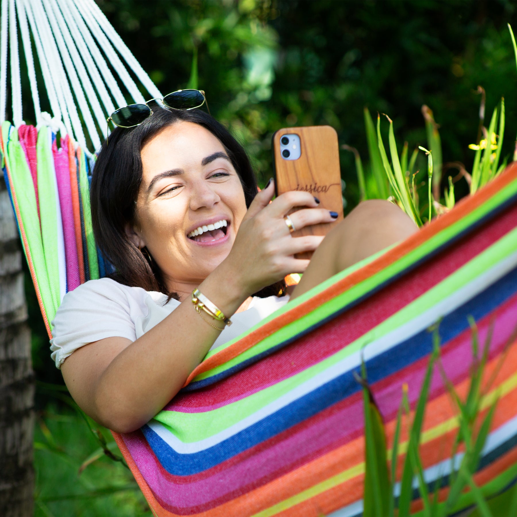 Woman smiling at her cellphone while relaxing in a Bliss Hammocks 40-inch Wide Hammock outside.