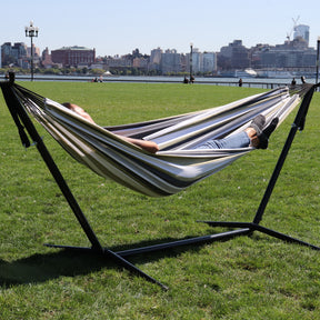 Girl relaxing outside in the Bliss Hammocks 60-inch Wide Hammock & Built-in Stand. Part of the New York skyline is in the background.