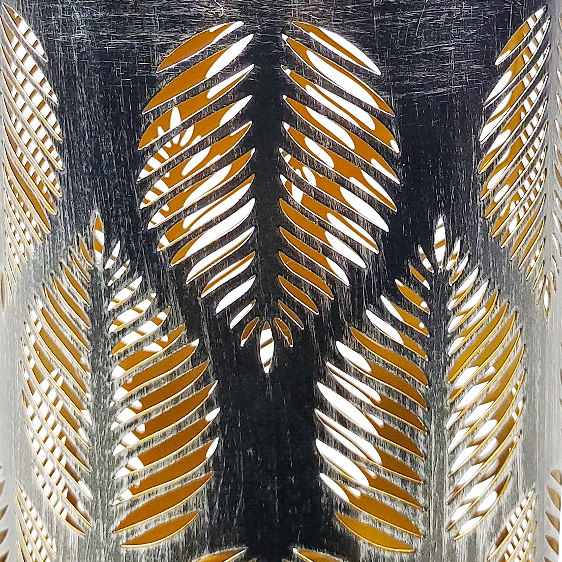 Close-up of a Bliss Outdoors 9-inch Tall Decorative LED Lantern with tropical leaf design in the brushed silver variation showing its pattern and color.