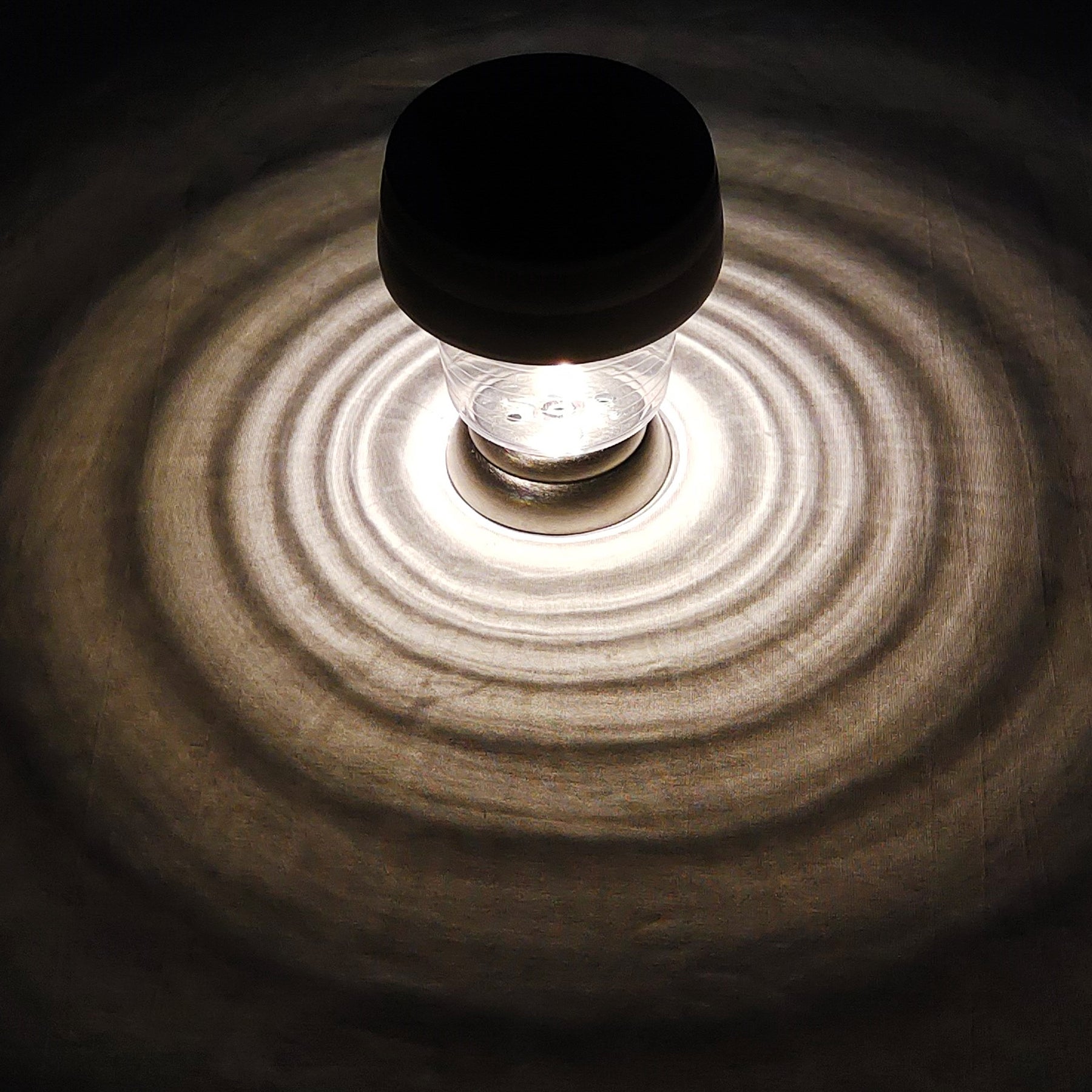 Bliss Outdoors 14-inch Tall Stainless Steel Solar Powered LED Pathway Light turned on and creating an ocean pattern with light on the surface around it.