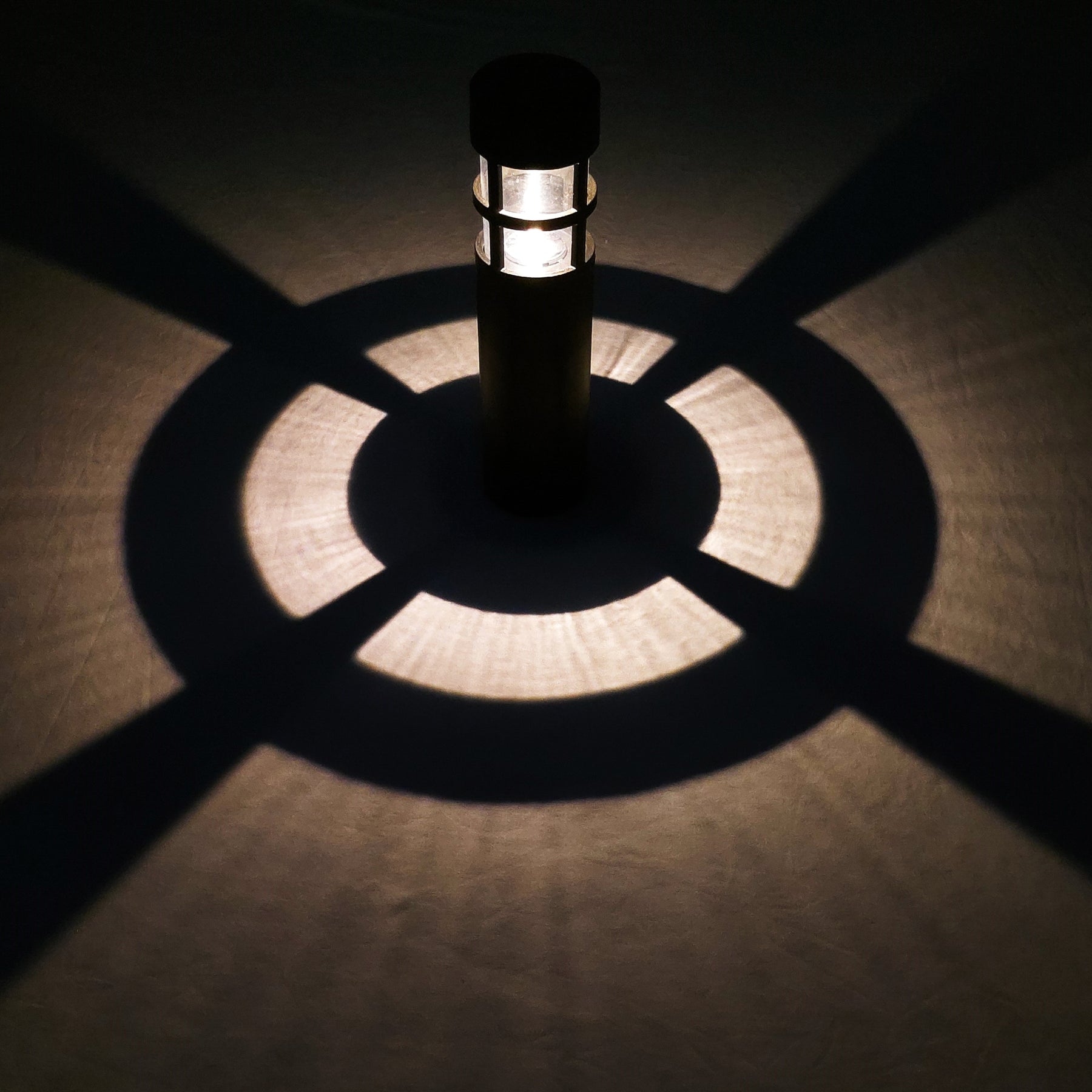 Bliss Outdoors 14-inch Tall Solar Powered LED Pathway Light with ABS Casing turned on and illuminating the ground around it.