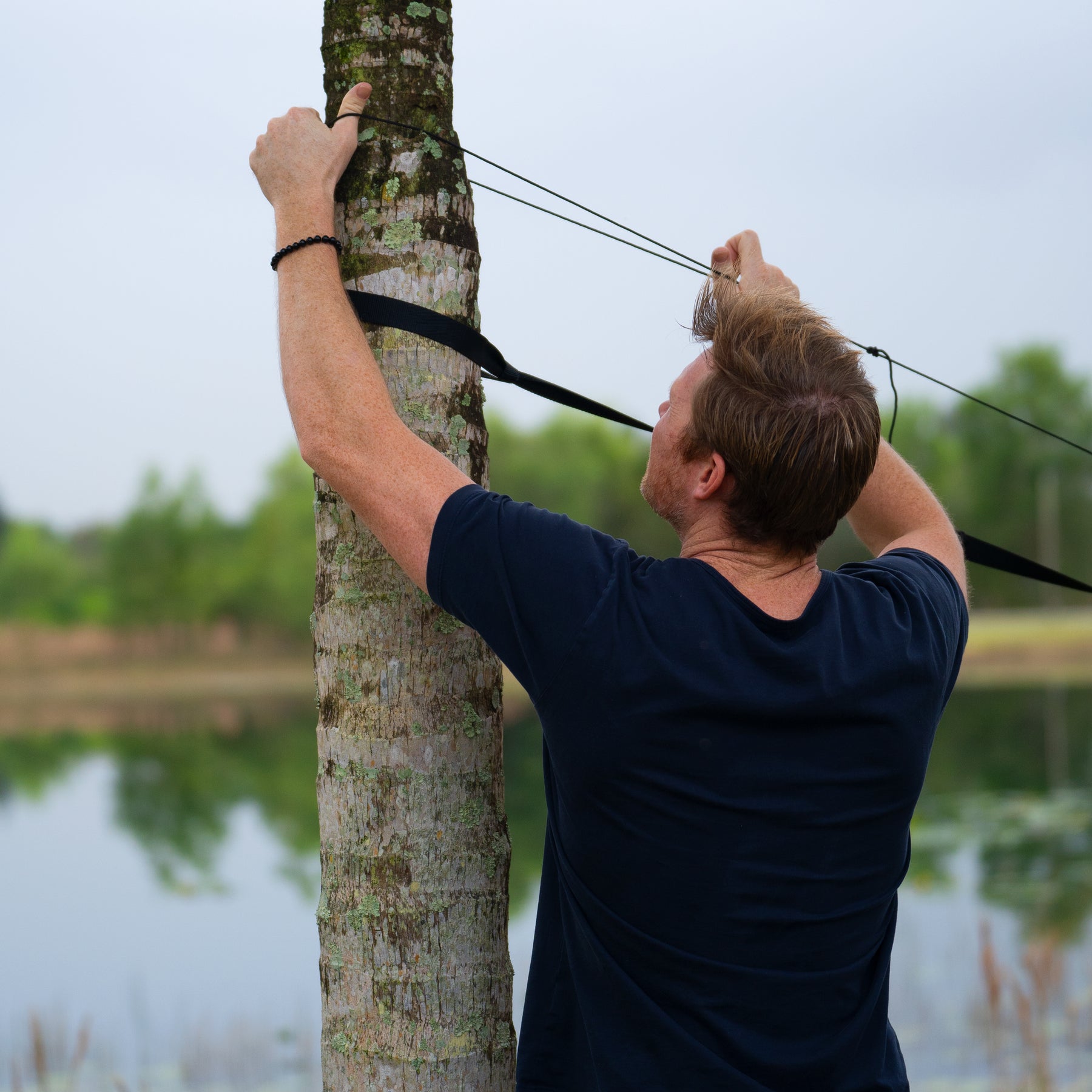 Man securing the mosquito net to the tree.