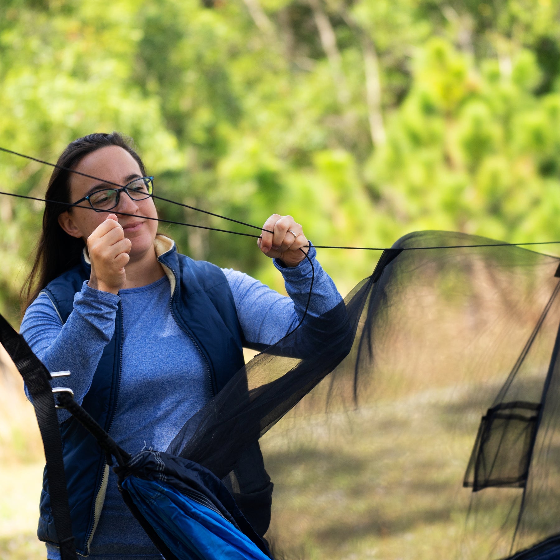 Woman setting up her Bliss Hammocks 54-inch Wide Hammock in a Bag with mosquito net.