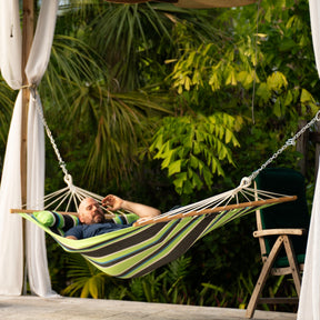 Man relaxing in a Bliss Hammocks 48-inch Wide Caribbean Hammock outside on the patio.