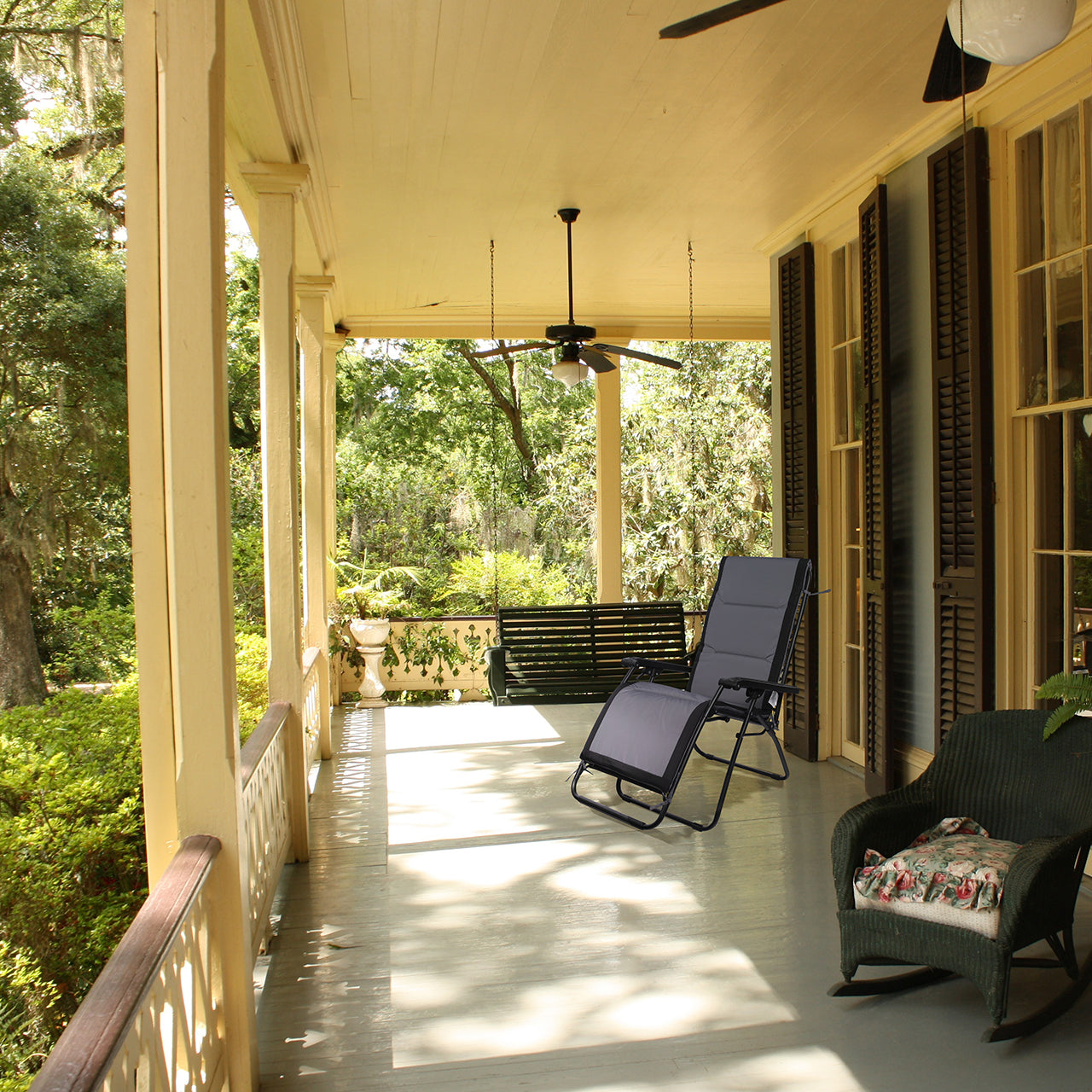 Bliss Hammocks Gravity Free Recliner Seat Cushion laid on top of a chair sitting on a front porch.