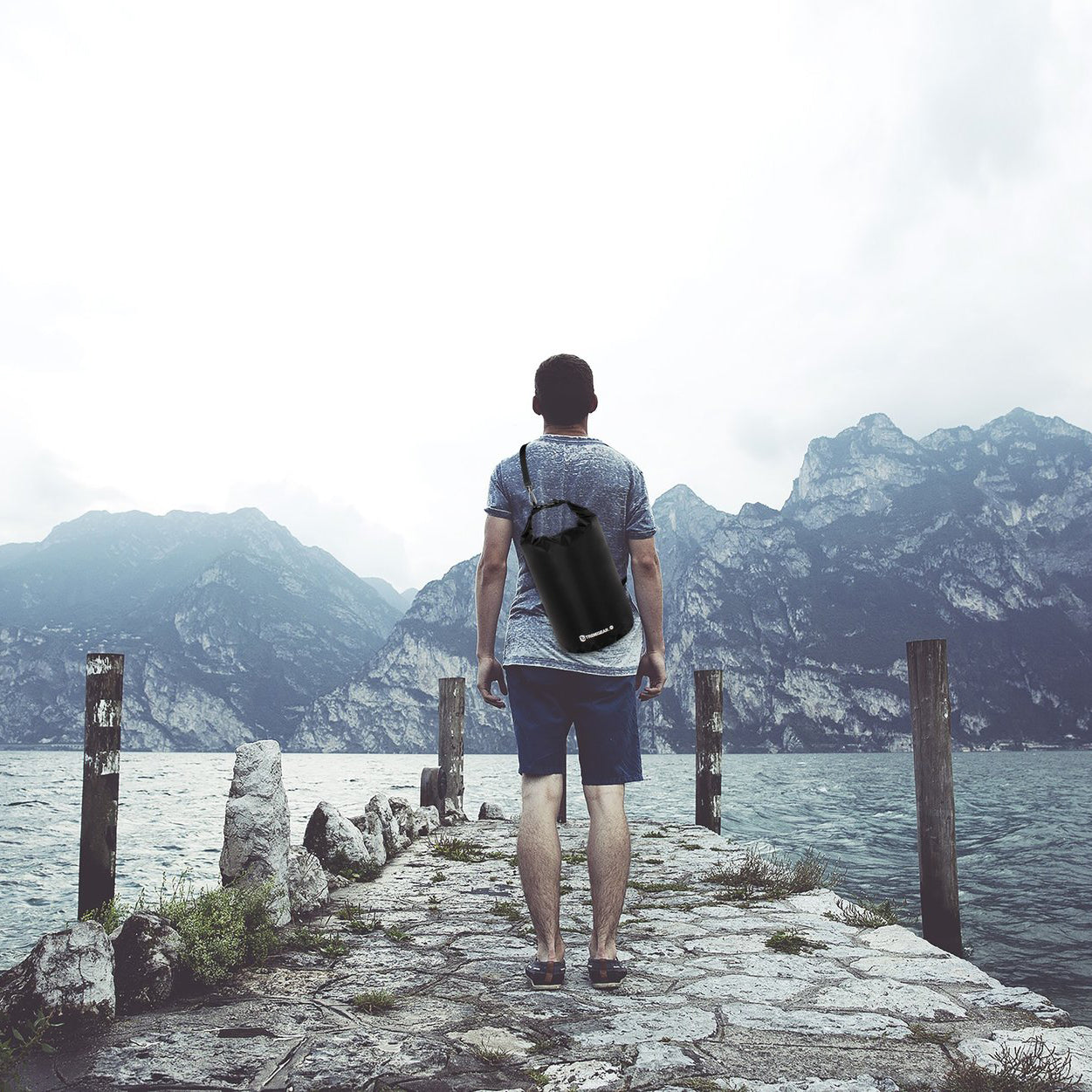 Person looking out onto a lake and mountains wearing the TrailGear 5 liter Heavy-Duty Dry Bag on their back.