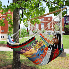 Girl relaxing in the Bliss Hammocks 40-inch Multi-Color Island Rope Hammock Chair hanging from a tree.