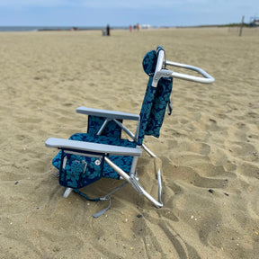 Side view of the blue flower backpack beach chair on the sand.