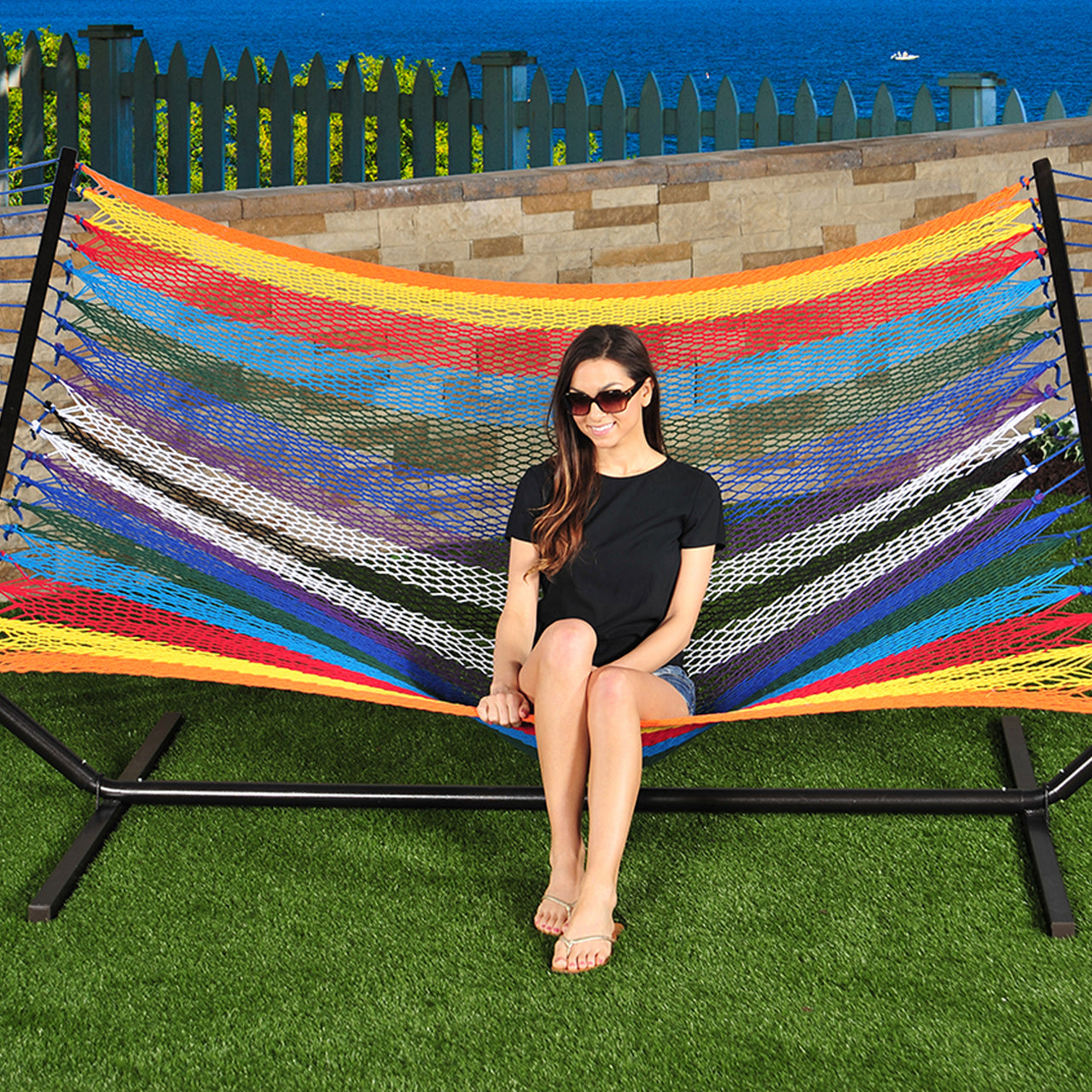 Girl sitting in the Bliss Hammocks 60-inch Wide Multi-Color Rope Hammock.