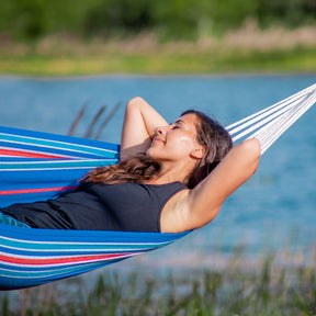 Woman relaxing outside in the Bliss Hammocks 40-inch Wide Hammock with a body of water in the background.