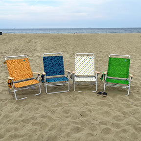 4 foldable beach chairs on the sand, each with a different color and pattern.