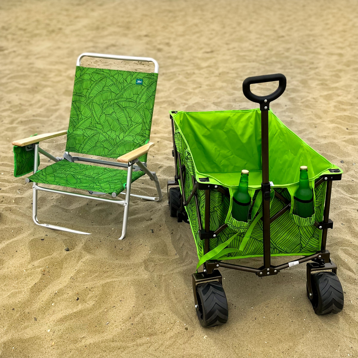 Green Banana Leaves Collapsible Beach Wagon with bottles in the cup holders, next to a matching beach chair.