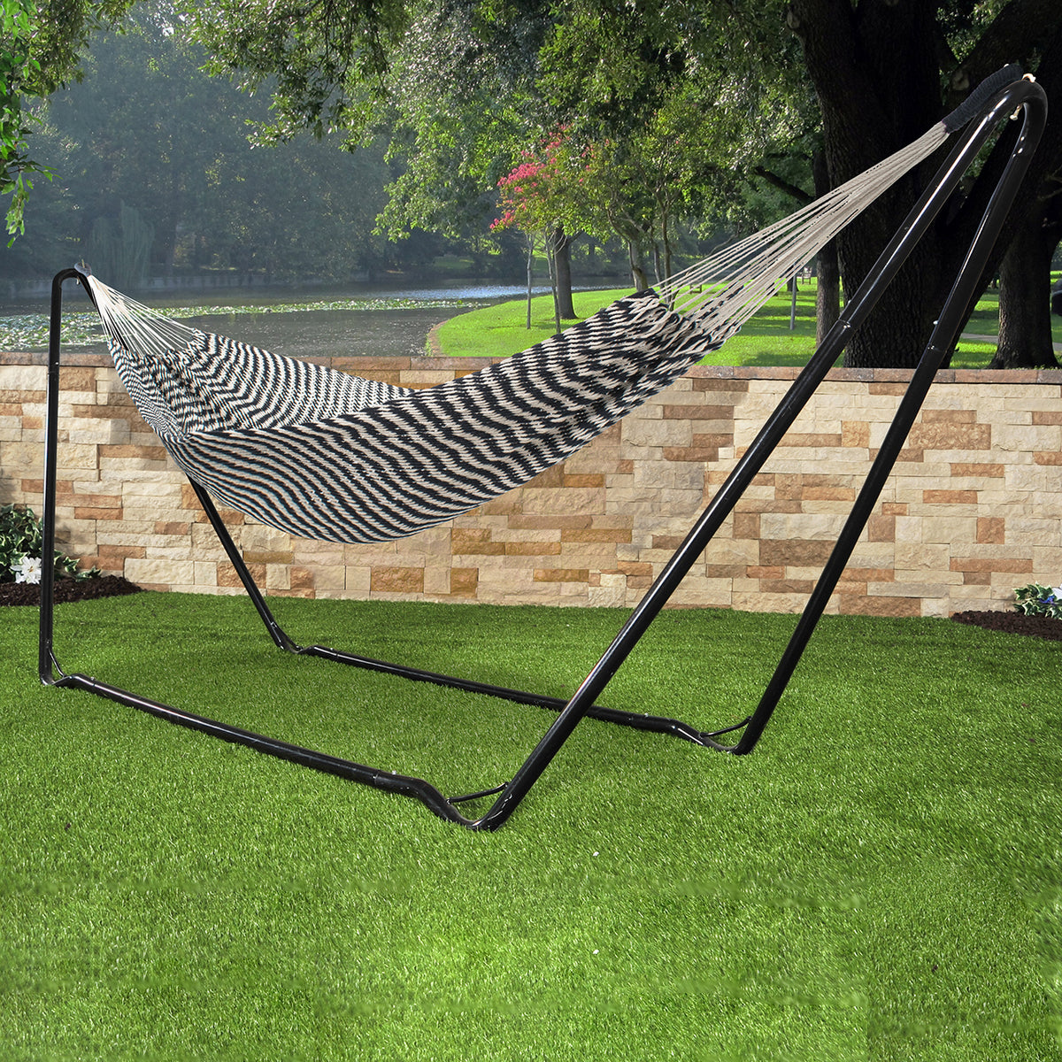 Bliss Hammocks 39-inch Brazilian Style Rope Hammock with Braided Rope Ends with a zebra-like pattern attached to a Bliss Hammocks Stand outside in the grass.