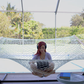 Woman wearing headphones and on her laptop sitting in a Bliss Hammocks 60-inch Wide Polyester Rope Hammock.