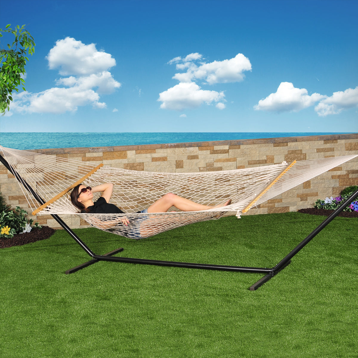 Woman laying outside in a hammock secured to the 15-foot black stand.