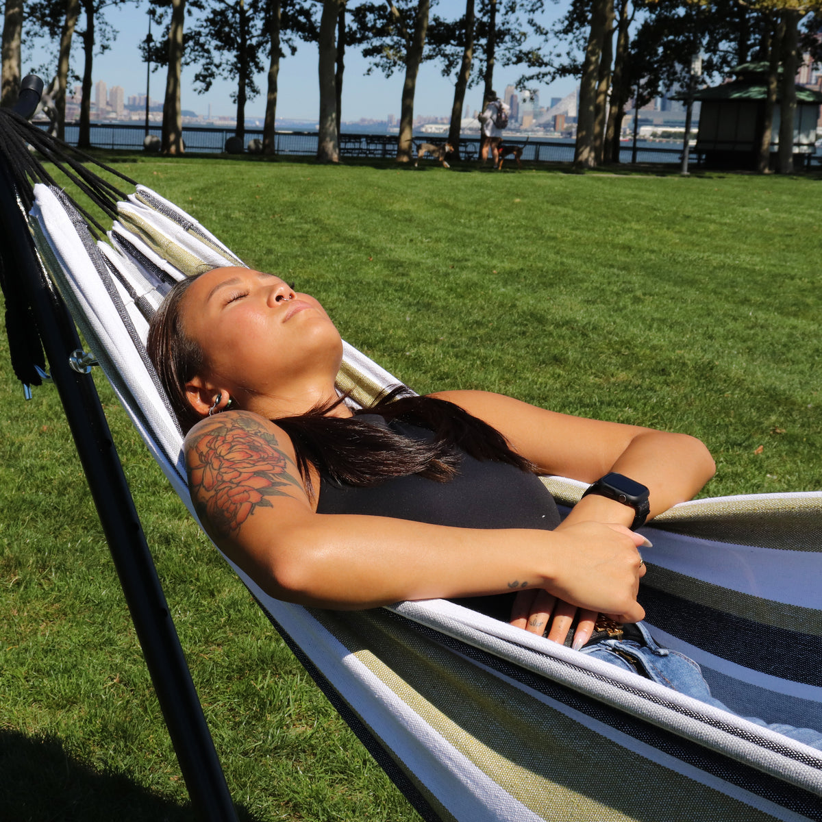 Girl relaxing outside in the Bliss Hammocks 60-inch Wide Hammock & Built-in Stand with the sun shining on her.