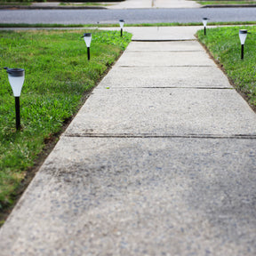 Solar powered LED pathway lights lined along the sides of a front walkway.