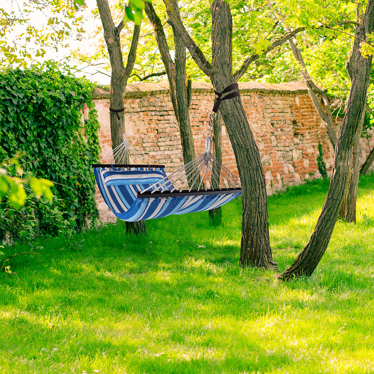 Bliss Hammocks 48-inch Ventaleen Oversized Hammock with Pillow and Spreader Bars in the ocean blue variation hanging outside between two trees.