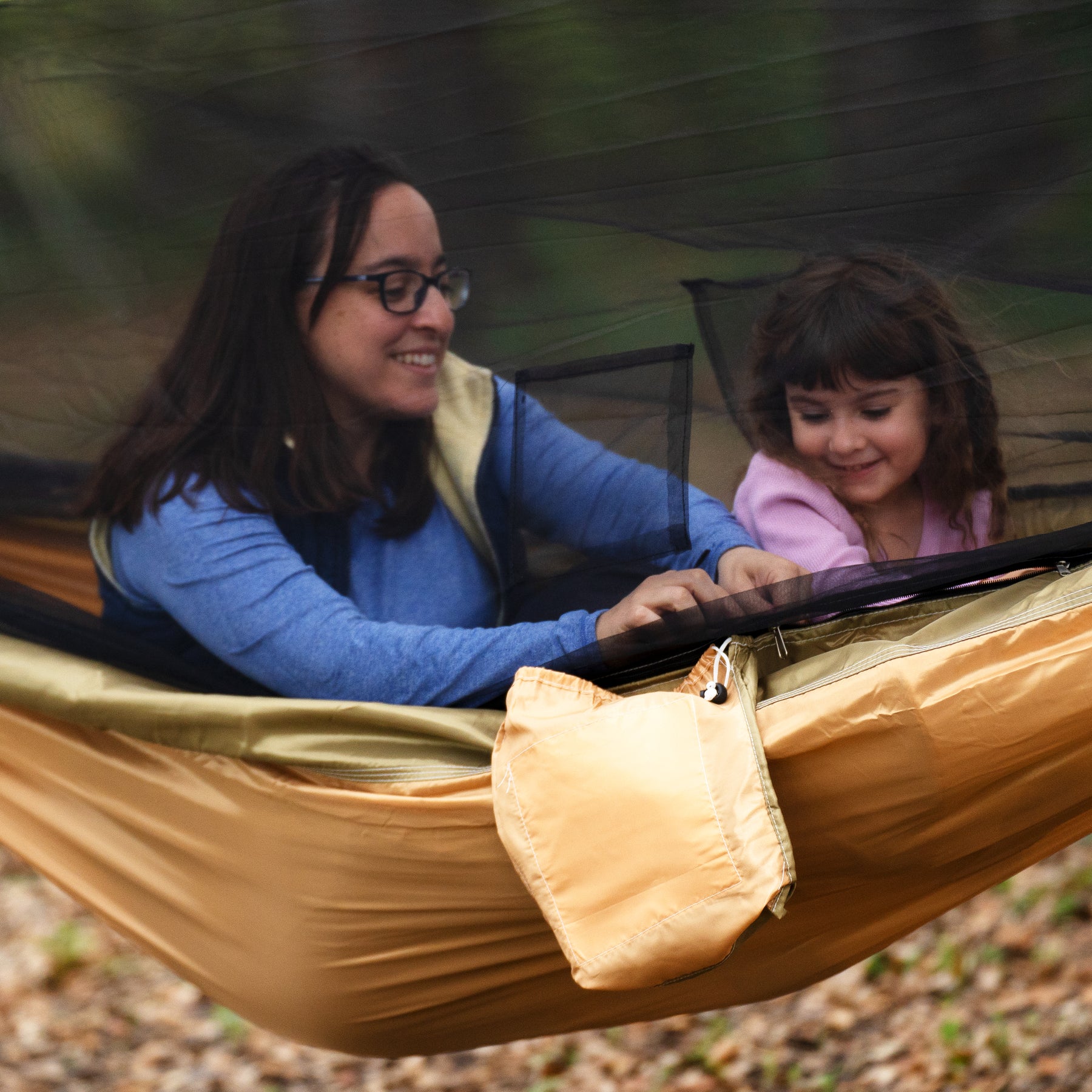 Woman and young girl sitting in a Bliss Hammocks 54-inch Wide Hammock in a Bag with mosquito net.
