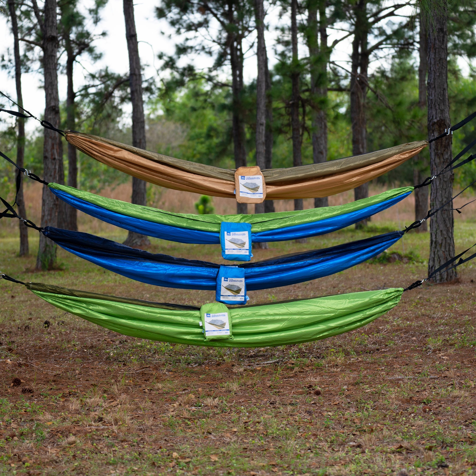All four variations of the Bliss Hammocks 54-inch Wide Hammock in a Bag with mosquito net and tree straps hung between trees in the woods.