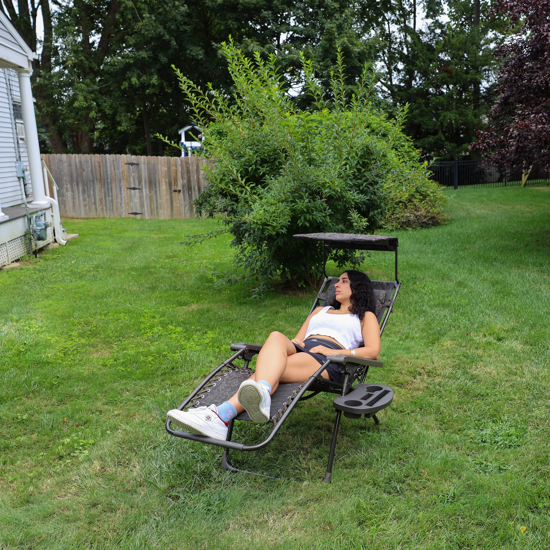 Girl reclined in the 26-inch Brown Jacquard Zero Gravity Chair on a lawn.