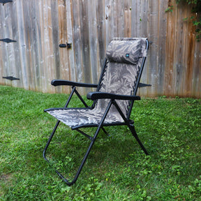 26-inch Reclining Platinum fern Sling Chair on a lawn next to a fence.