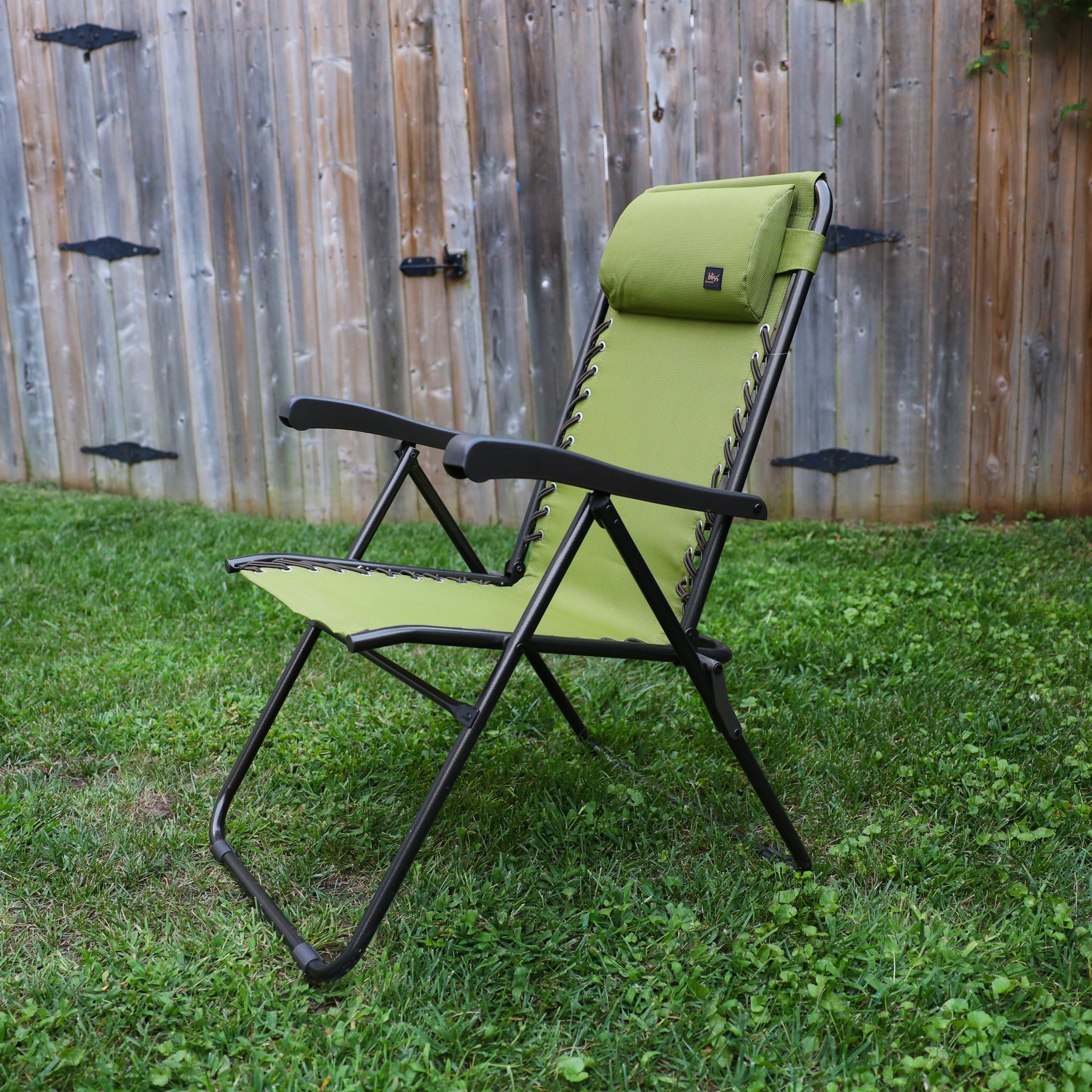 26-inch Reclining Sage green Sling Chair on a lawn next to a fence.