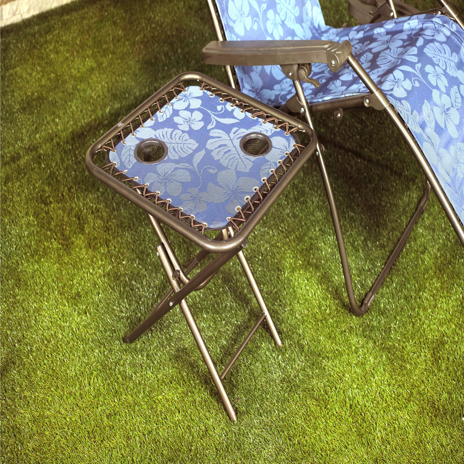 Bliss Hammocks 20-inch Folding Side Table with 2 Built-In Cup Holders in the blue flowers variation in the grass next to a gravity free chair.