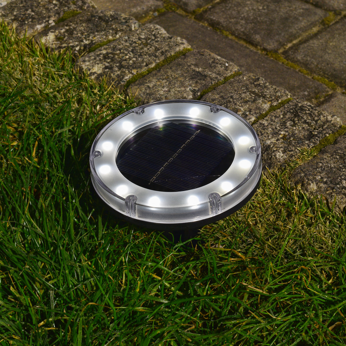 Bliss Outdoors Solar Powered Disc LED Pathway Light turned on and illuminating white.
