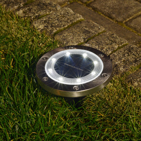 Bliss Outdoors Solar Powered LED Metal Disc Pathway light in the ground lighting up white.