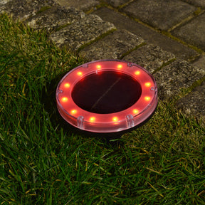 Bliss Outdoors Solar Powered Disc LED Pathway Light turned on and illuminating red.