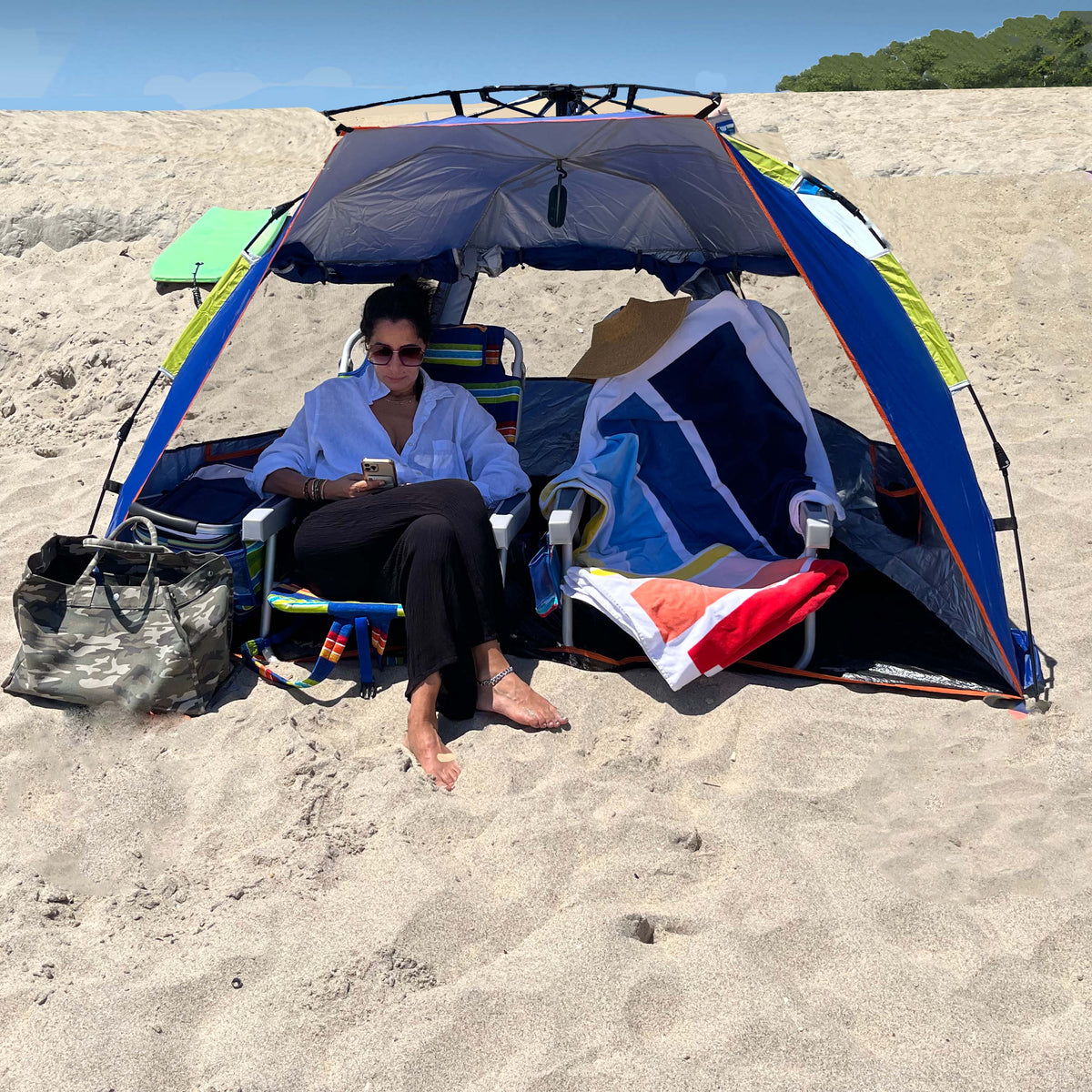 Woman sitting on the beach in the Bliss Hammocks Pop-Up Beach Tent with a collapsible design.