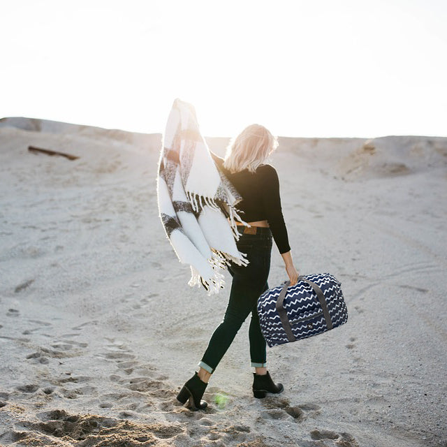 Girl walking in the sand and carrying the TrailGear 30 Liter Duffel Bag.