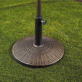 Bliss Outdoors Heavy-Duty Umbrella Base in the wicker variation in grass with an umbrella inside.