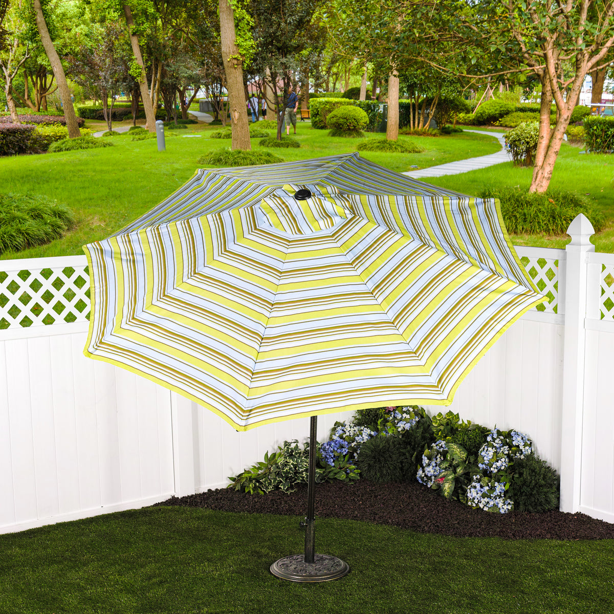 Bliss Outdoors 9-foot Patio Umbrella with Aluminum Pole in the Montauk Stripe variation in the backyard near a fence.