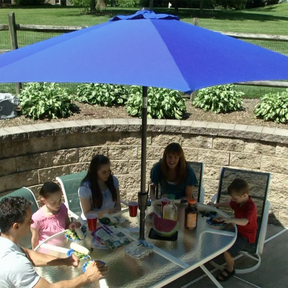 Family eating at a patio table under the Bliss Outdoors 9-foot Patio Umbrella with Aluminum Pole.